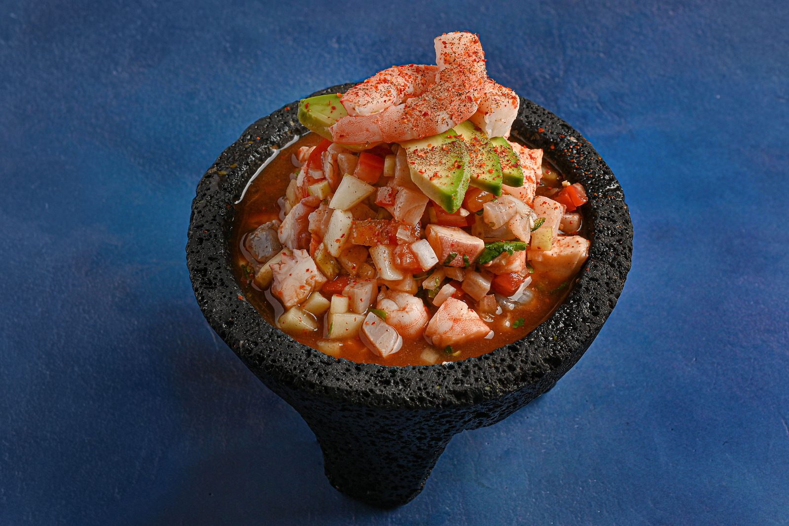 Mexican seafood cocktail served in a black lava molcajete with shrimp and octopus