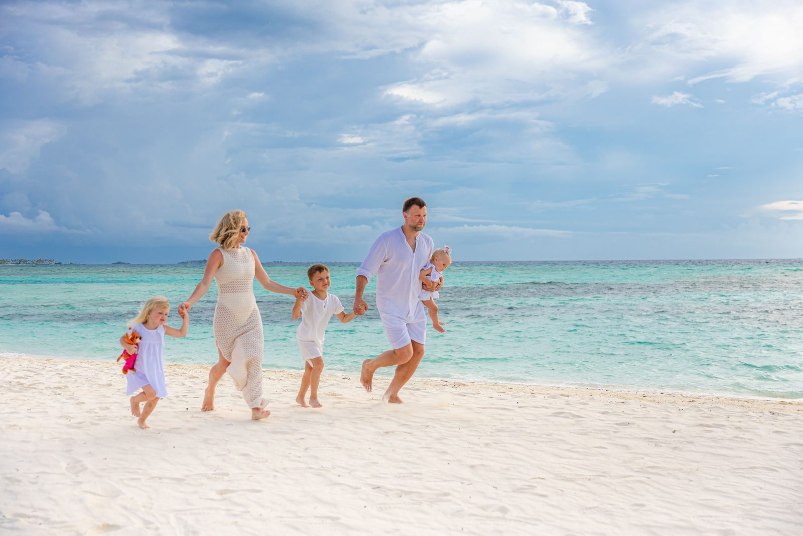 Family with young children walking a white-sand beach in Tulum