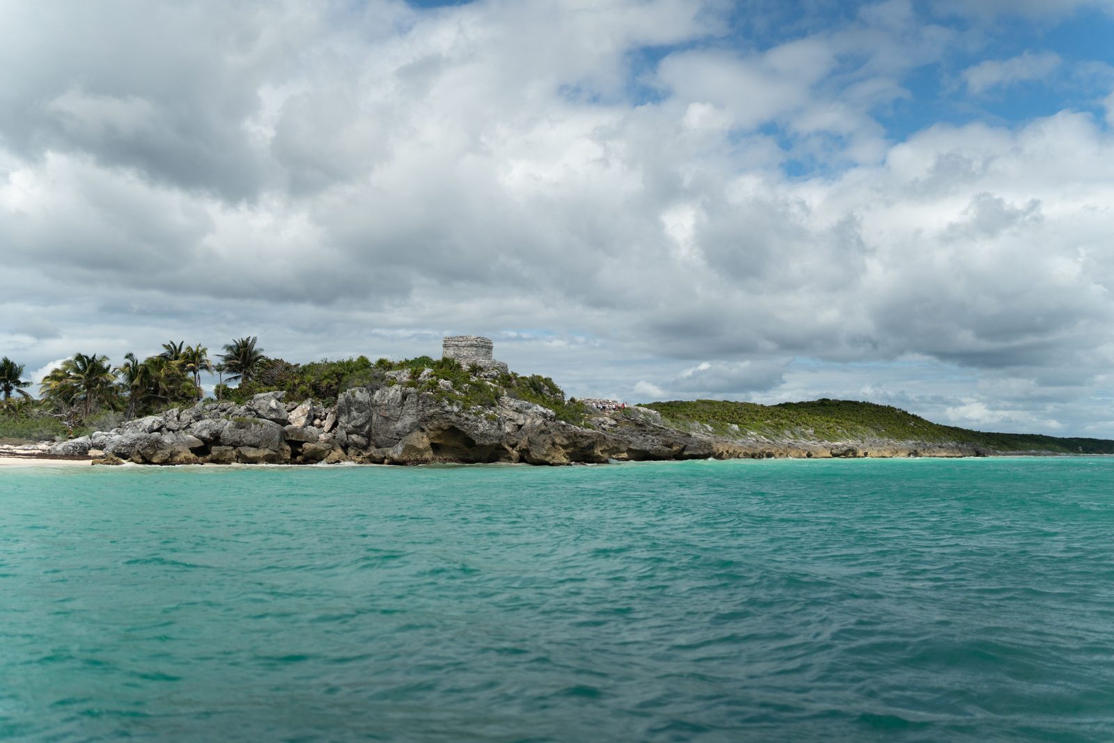 Turquoise water and rocky shore on the beach below the Tulum ruins